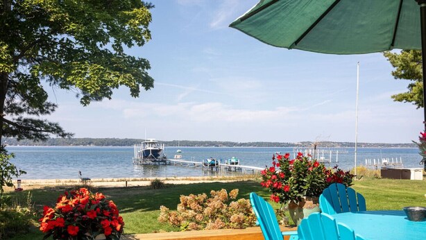 A deck with a view of a lake, a dock with boats, and a gazebo.