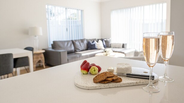 A modern living room with a dining area, featuring a round table with snacks and drinks.