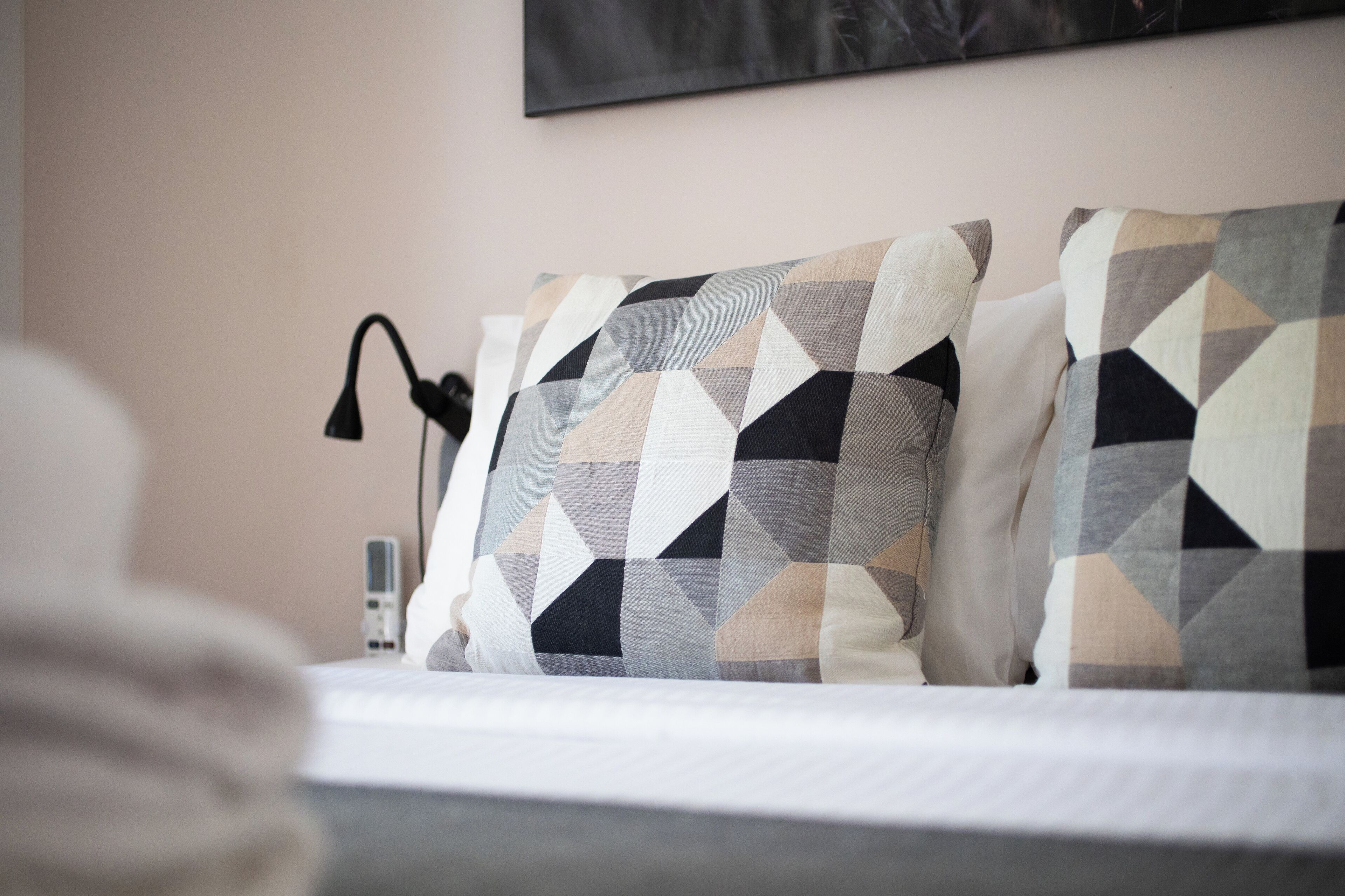 A neatly made bed with patterned pillows and a bedside lamp.