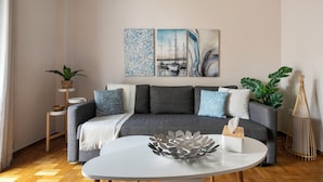 A living room with a grey sofa, a white coffee table, and a wall-mounted painting. - Selany's Chic Apt in the Heart of Athens (Athens)
