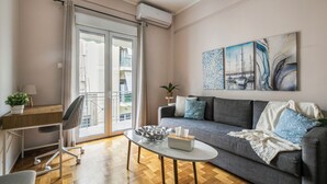 A modern living room with a sofa, a coffee table, a desk with a chair, and a balcony with a view. - Selany's Chic Apt in the Heart of Athens (Athens)