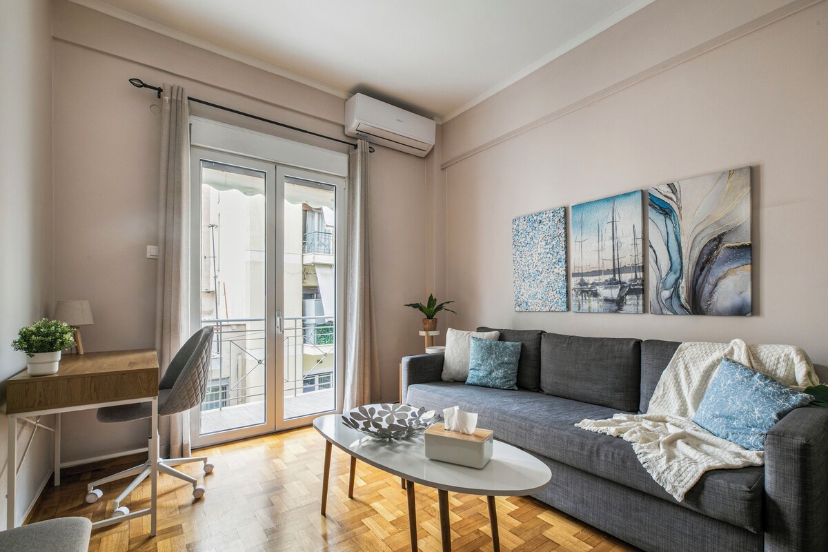 Een moderne woonkamer met een bank, een salontafel, een bureau met stoel en een balkon met uitzicht.
