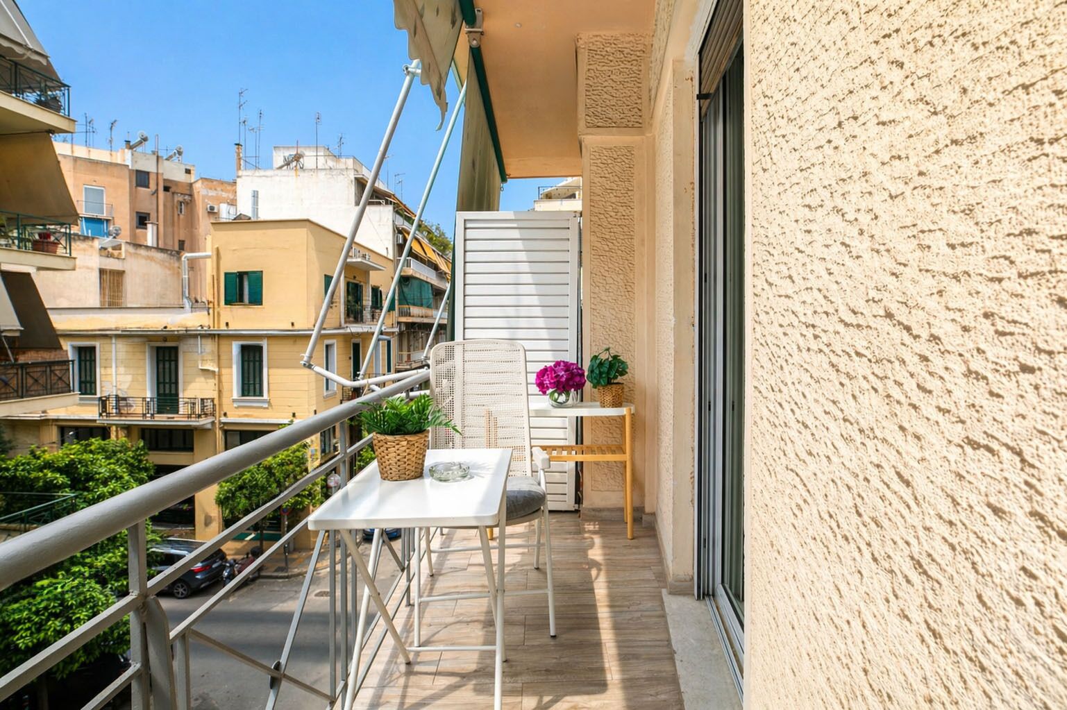 A balcony with a table, chairs, potted plants, and a railing.