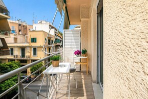 Een balkon met een tafel, stoelen, plantenbakken en een hekwerk.