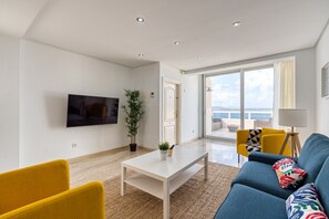 A modern living room with a flat-screen TV, a white coffee table, a blue sofa, yellow armchairs, and a large window with a view. - Beachfront House in Las Palmas With Terrace (Las Palmas de Gran Canaria)