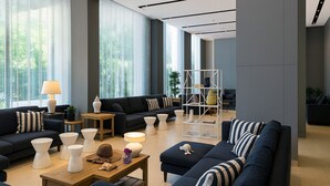 Un salon moderne avec des canapés foncés, des tables d’appoint blanches et une table basse en bois.