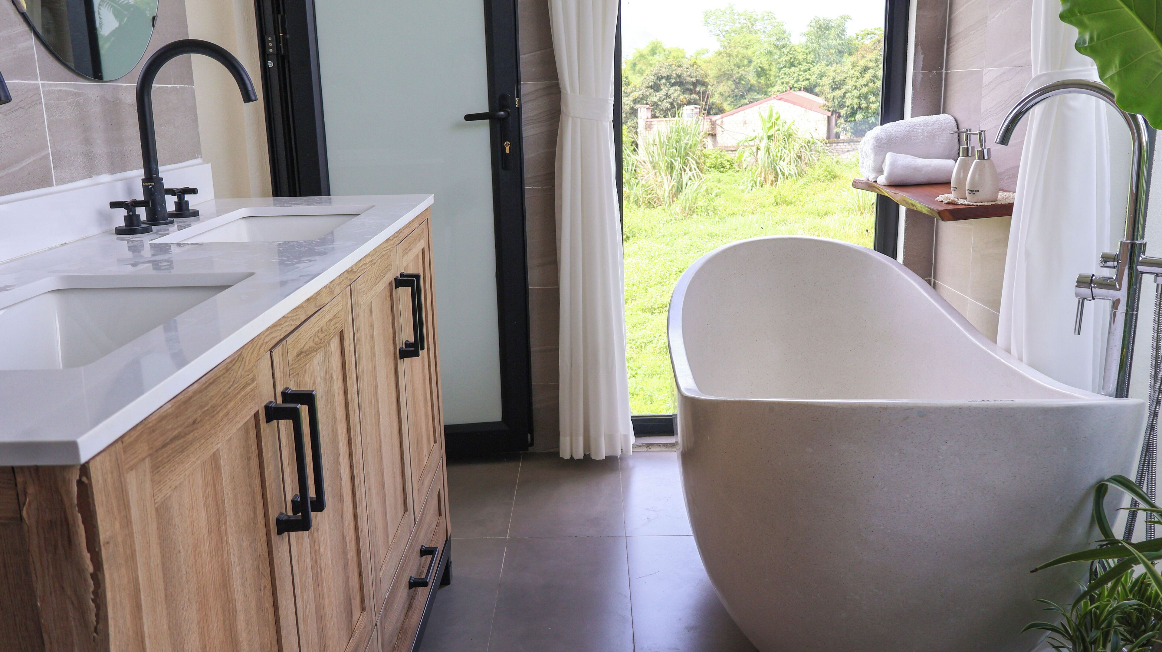 A modern bathroom with a freestanding bathtub, a large mirror, and a wooden vanity.