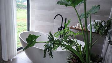 Un baño moderno con una bañera independiente, un ventanal grande y vistas al exterior.