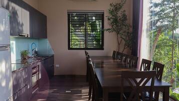 Uma cozinha moderna com mesa e cadeiras, uma janela com persianas e uma planta em vaso.