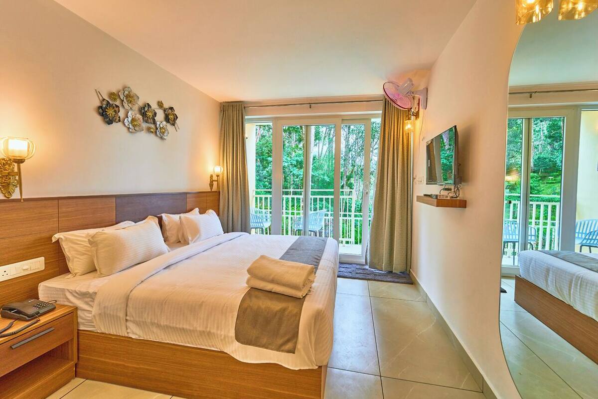 Une chambre bien éclairée, avec un grand lit, une table de chevet avec un téléphone et un téléviseur fixé au mur.