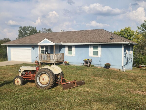 Een gelijkvloers huis met garage, veranda en gazon.