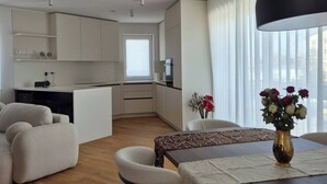 Una cocina moderna con armarios blancos, un comedor con mesa y sillas de madera, y una sala de estar con sofá.