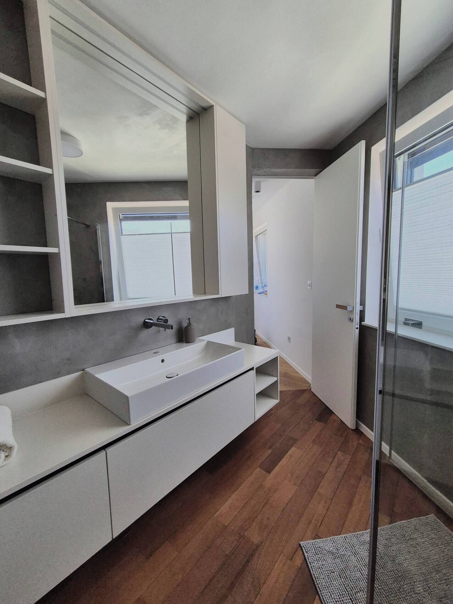 Un baño moderno con un espejo grande, tocador blanco y cabina de ducha de vidrio.