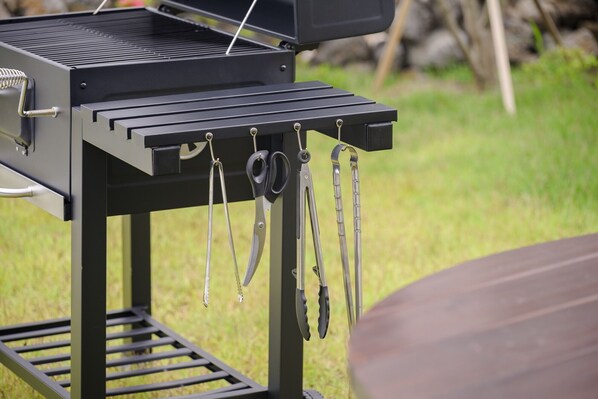 Un barbecue équipé de plusieurs ustensiles suspendus à un porte-ustensiles.