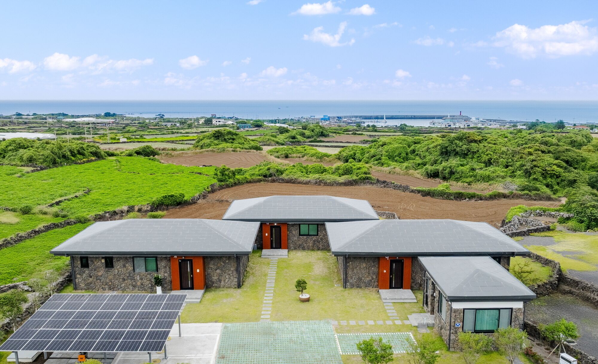 A modern house with three separate units, each with a distinct entrance and a small garden area.