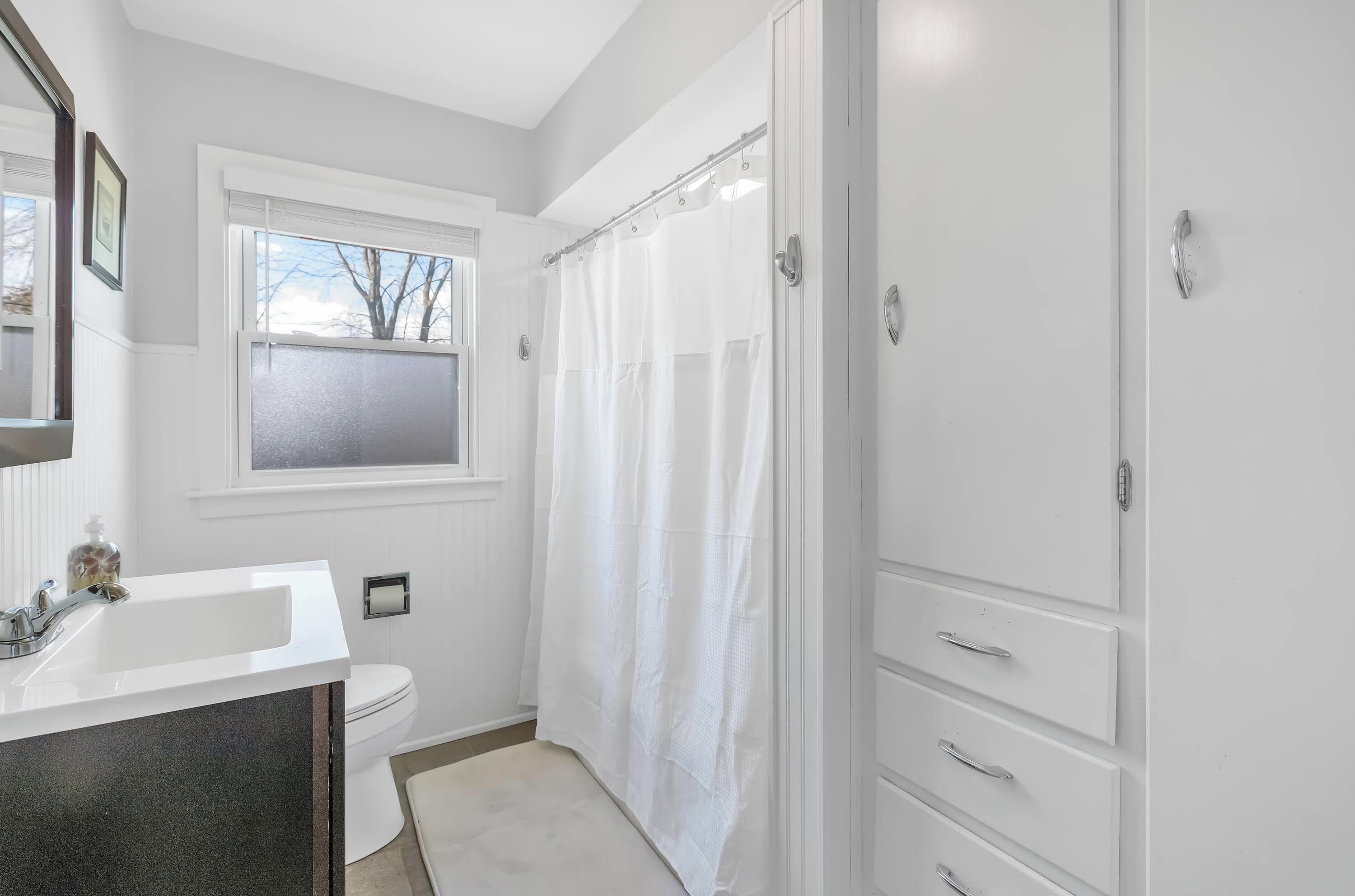 A bathroom with a white sink, toilet, and shower curtain.