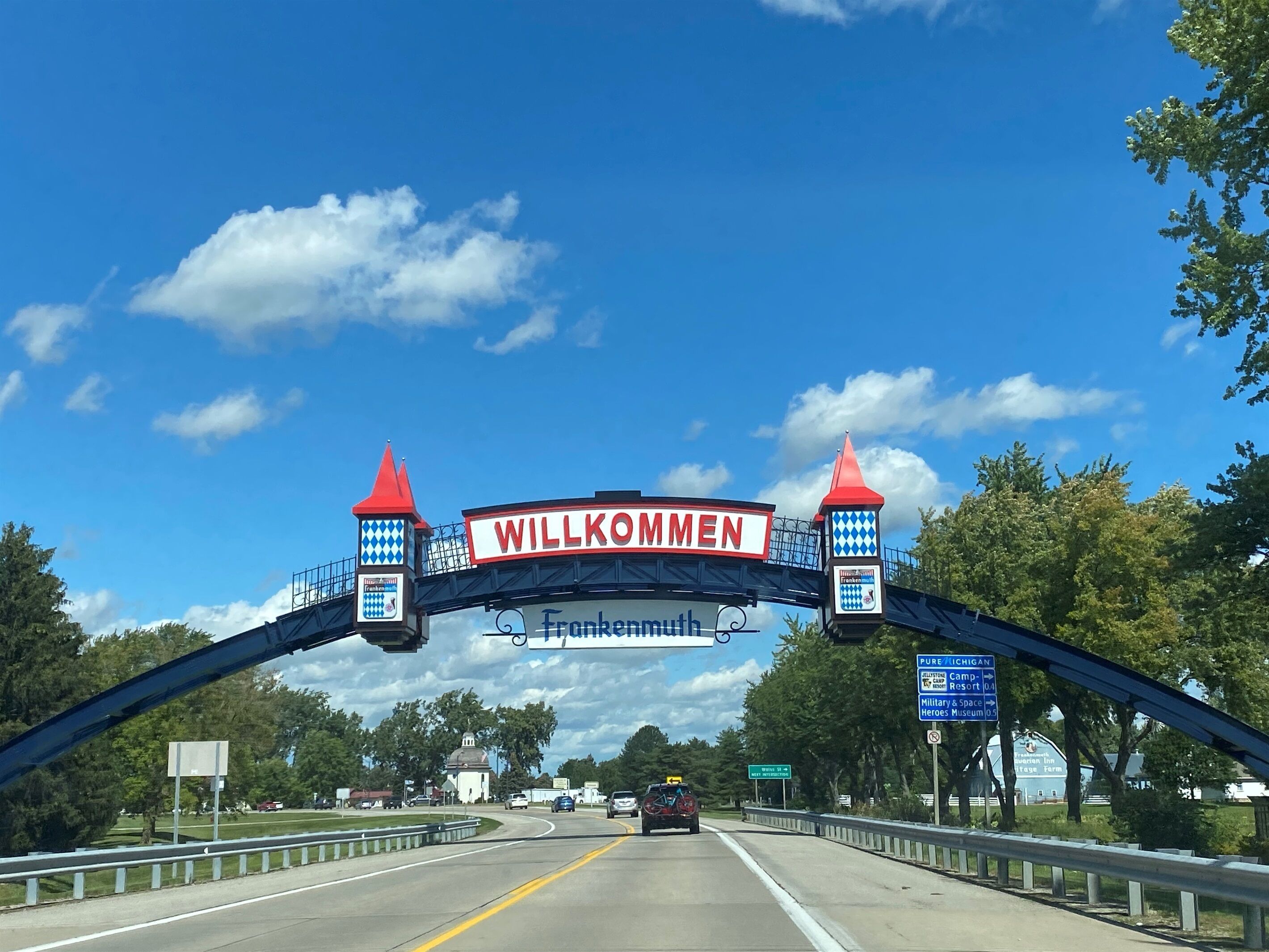 Motorvejsindgang med et 'Willkommen' skilt, en hvid kirke og et 'Pure Michigan' skilt.