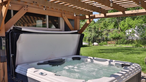 Un jacuzzi bajo una pérgola de madera, con una ventana encima.