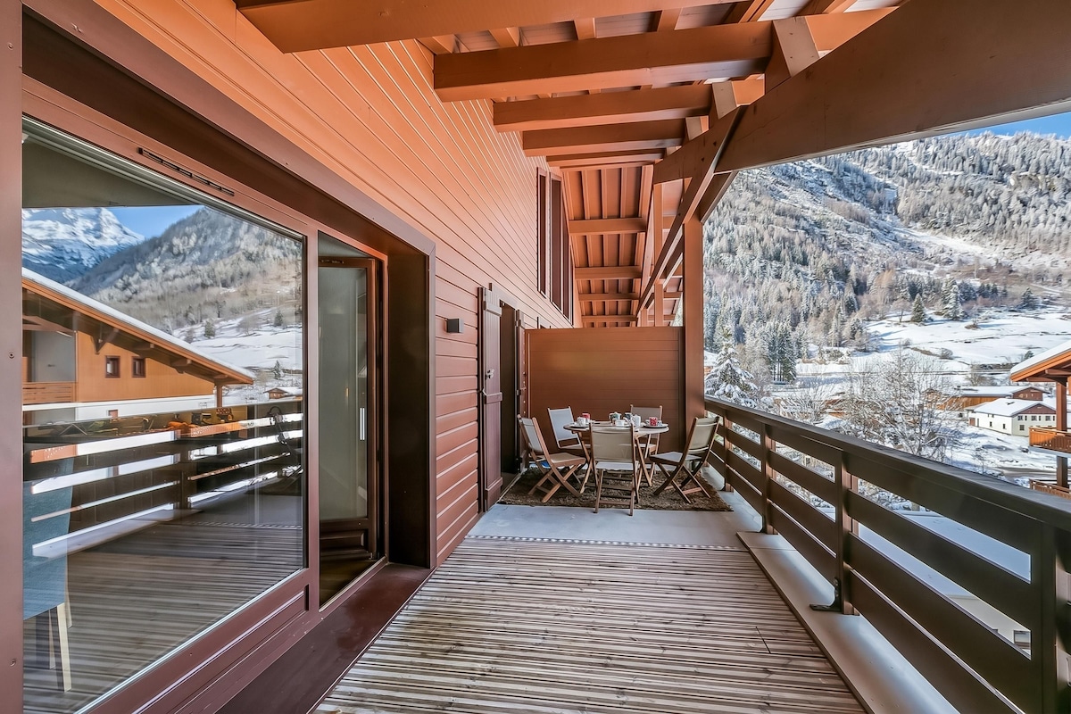 Un balcon en bois offrant une vue sur un paysage montagneux enneigé.
