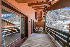 Un balcon en bois offrant une vue sur un paysage montagneux enneigé.