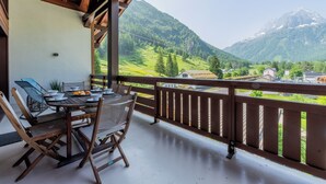 A balcony with a table and chairs, overlooking a mountainous landscape. - l Ours Bleu Apartments (Vallorcine)