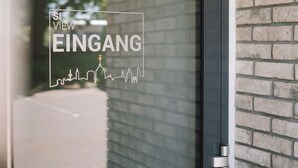 Een glazen deur met uitzicht op een bakstenen muur en een stadsachtergrond.