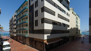 A multi-story building with a restaurant on the ground floor, a parking area, and a pedestrian zone with a clear view of the sea. - Apartment in Las Canteras by the Beach (Las Palmas de Gran Canaria)