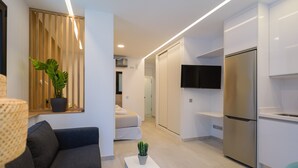 A modern living room with a sofa, a small table with a plant, and a TV mounted on the wall. - Apartment in Las Canteras by the Beach (Las Palmas de Gran Canaria)