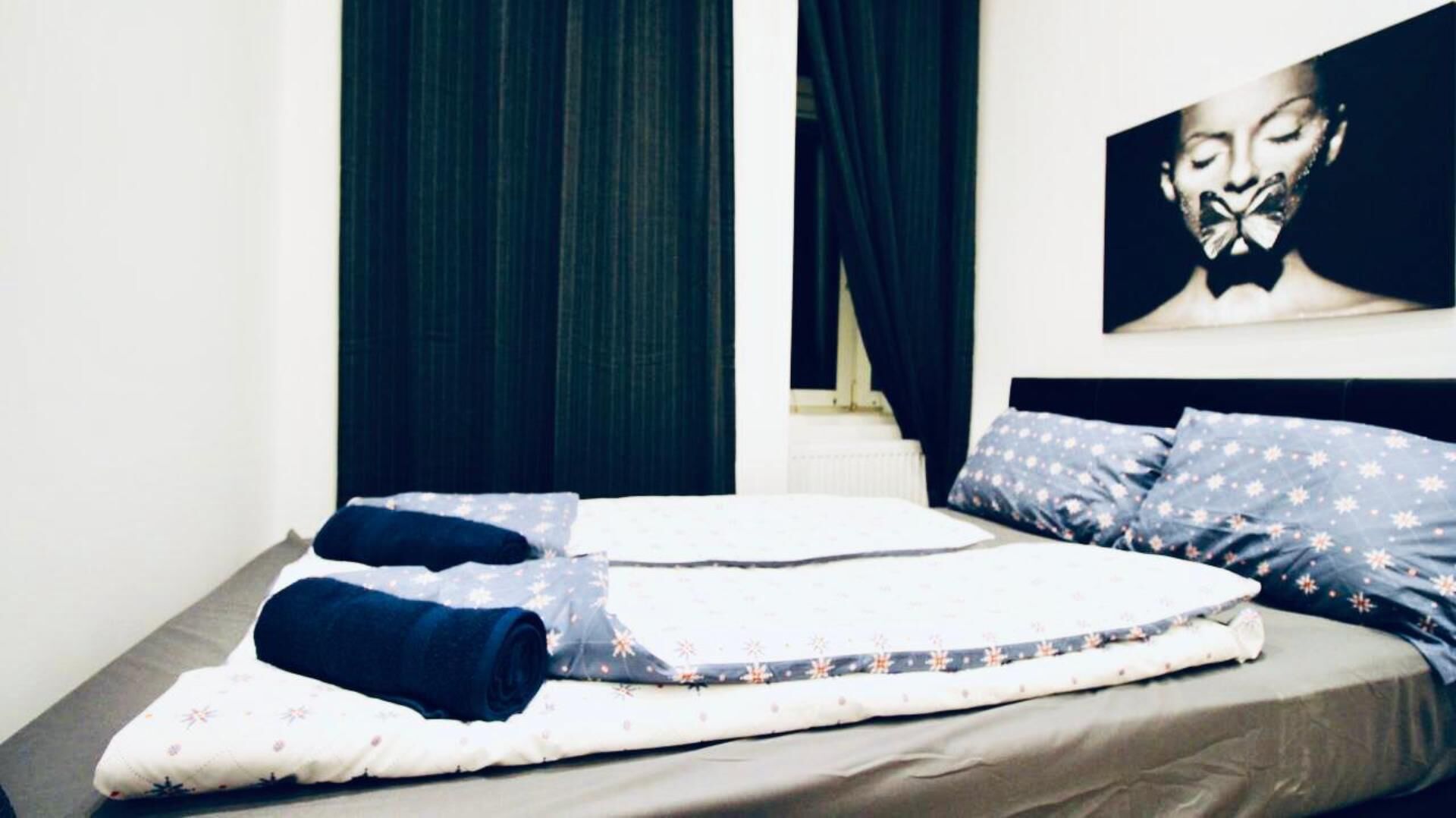 Un lit bien fait, recouvert d’une couvre-lit à motifs floraux blancs et bleus, agrémenté de coussins bleu foncé et d’une couverture bleu foncé.
