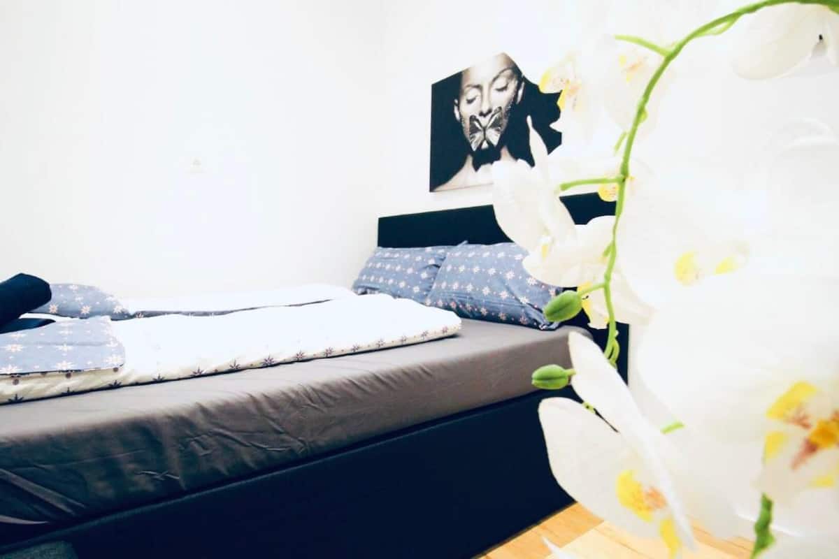 A bed with a grey mattress, a blue pillow with a star pattern, and a dark headboard.