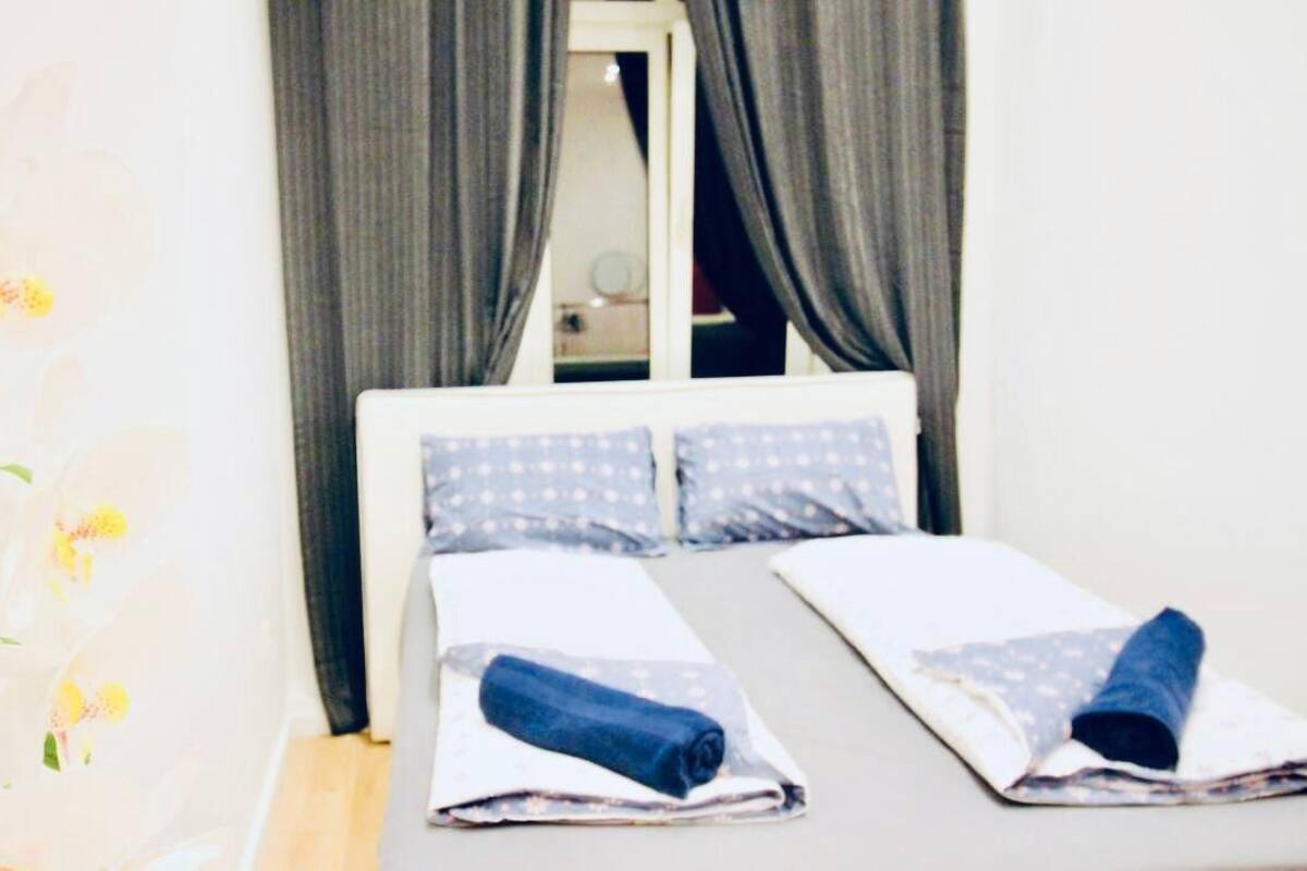 A hotel room with a bed, curtains, and a window.