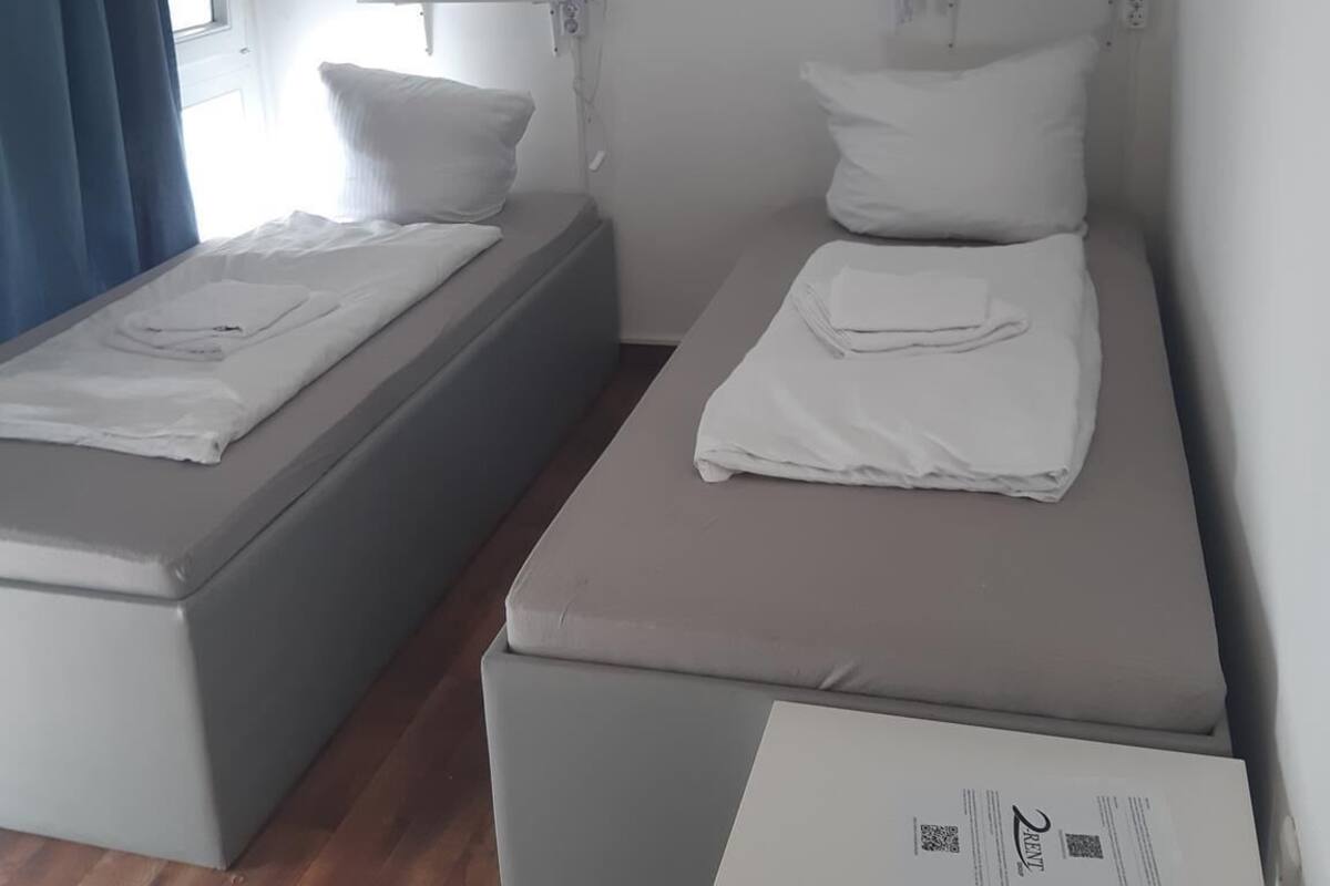 Une chambre double avec deux lits, une fenêtre avec des rideaux et un plancher en bois.