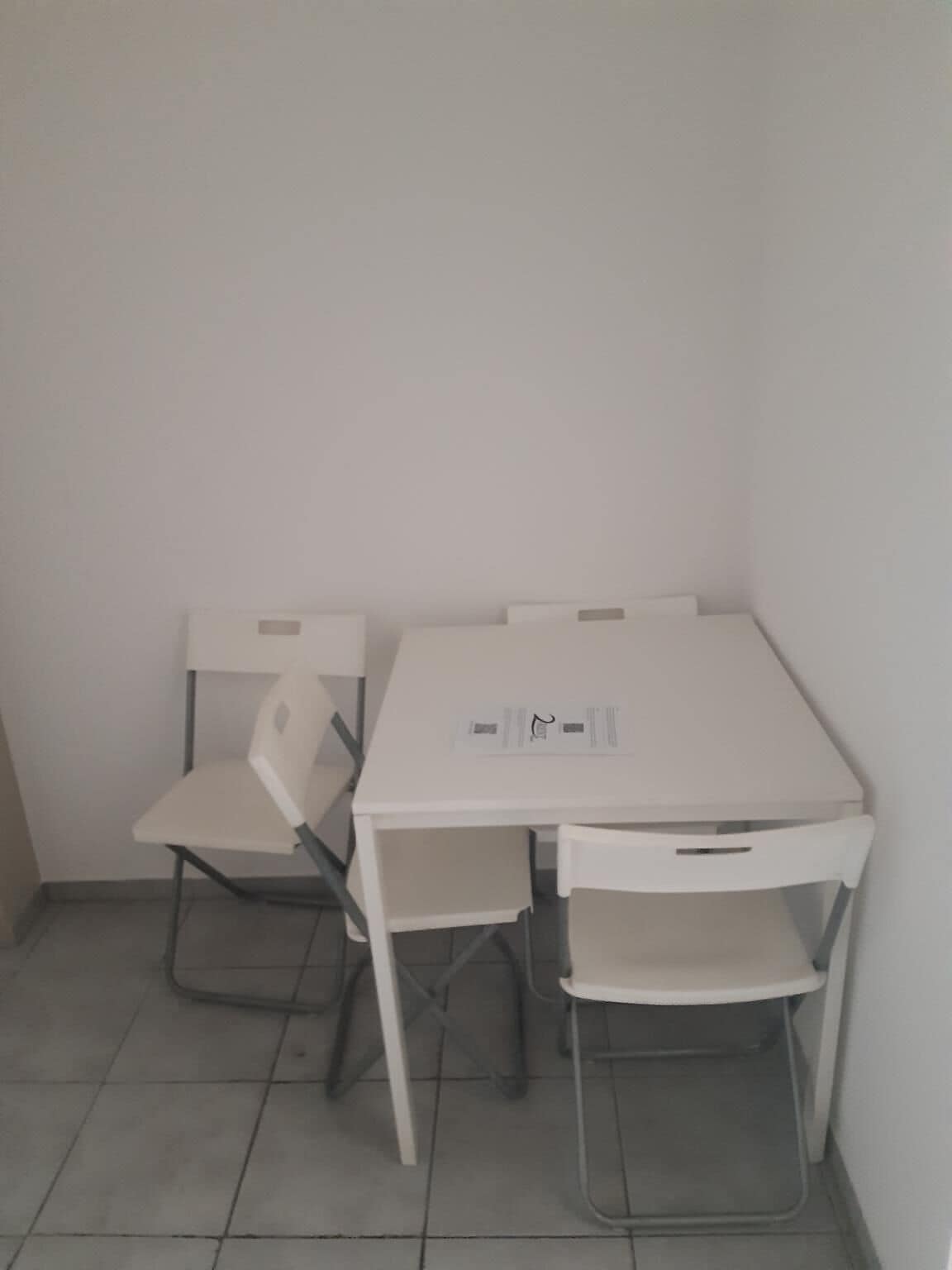 Ein kleiner, weißer Eckraum mit einem einzelnen weißen Tisch und zwei weißen Stühlen.