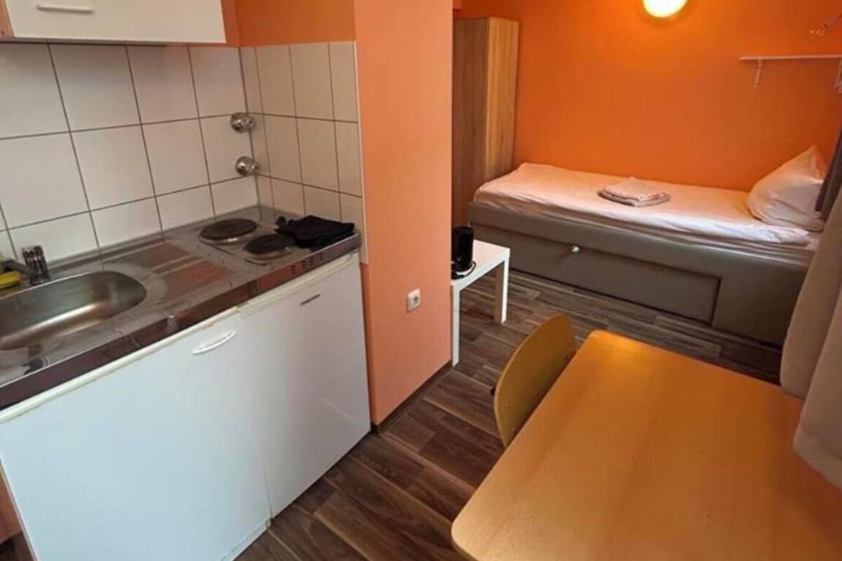 Une petite cuisine équipée comprenant un évier, une cuisinière et des placards blancs.