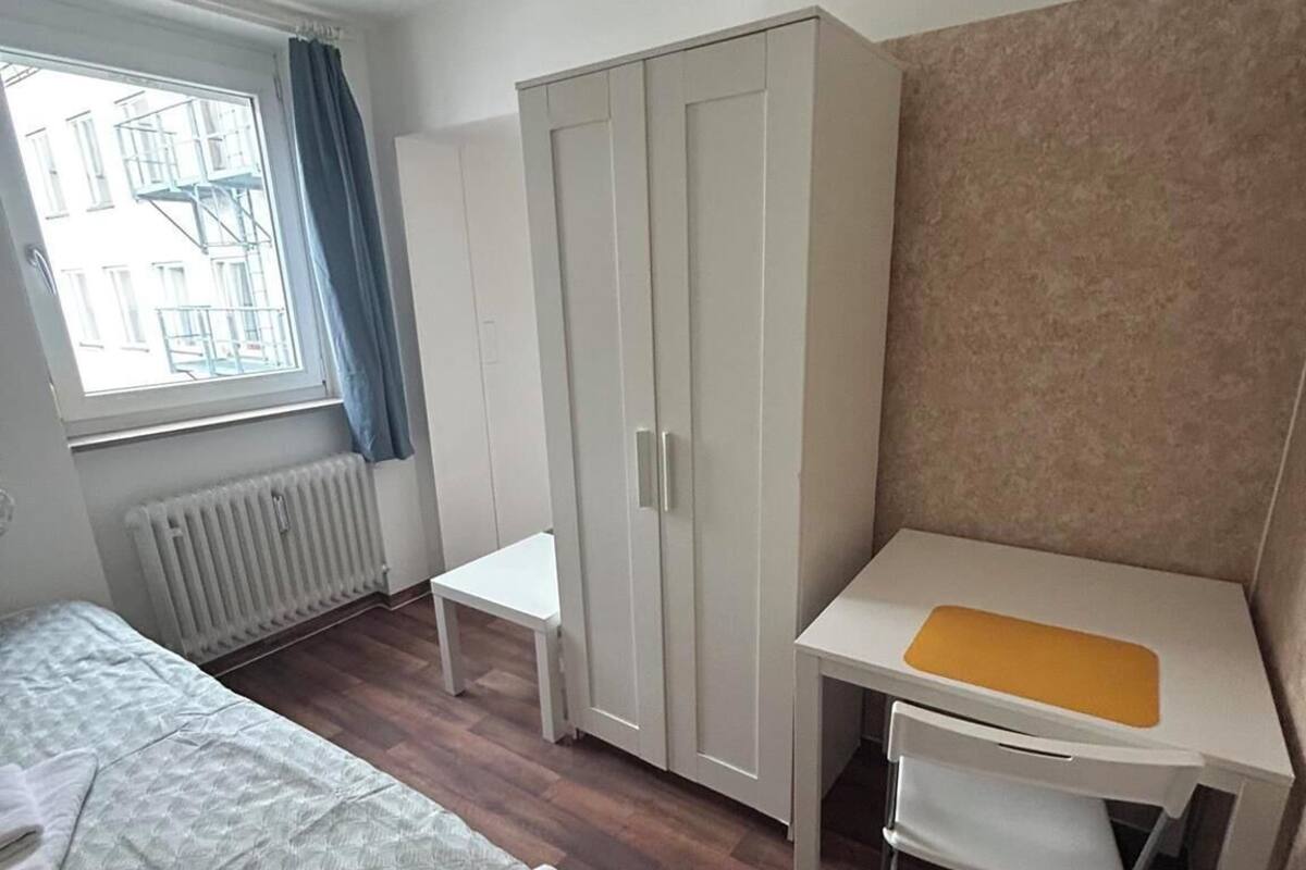 Une chambre à coucher avec un lit, un bureau, une armoire et un radiateur.