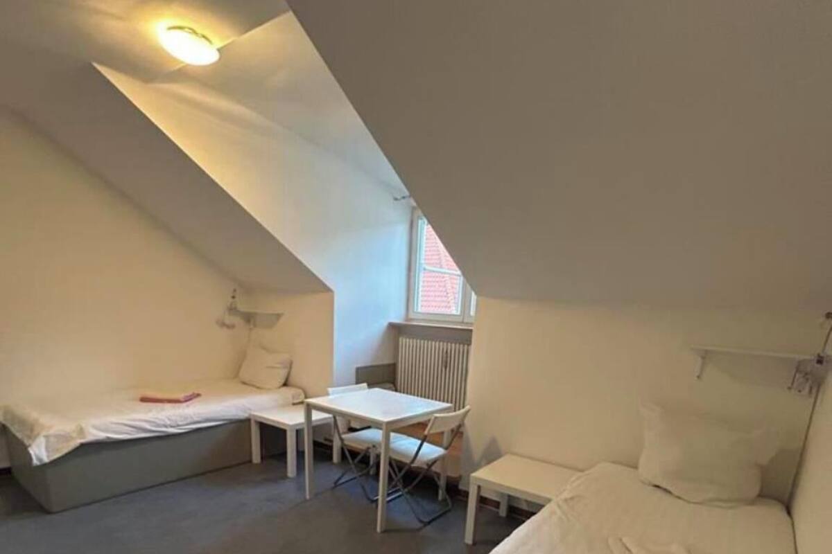 Une chambre de dortoir avec deux lits, une petite table et une chaise.