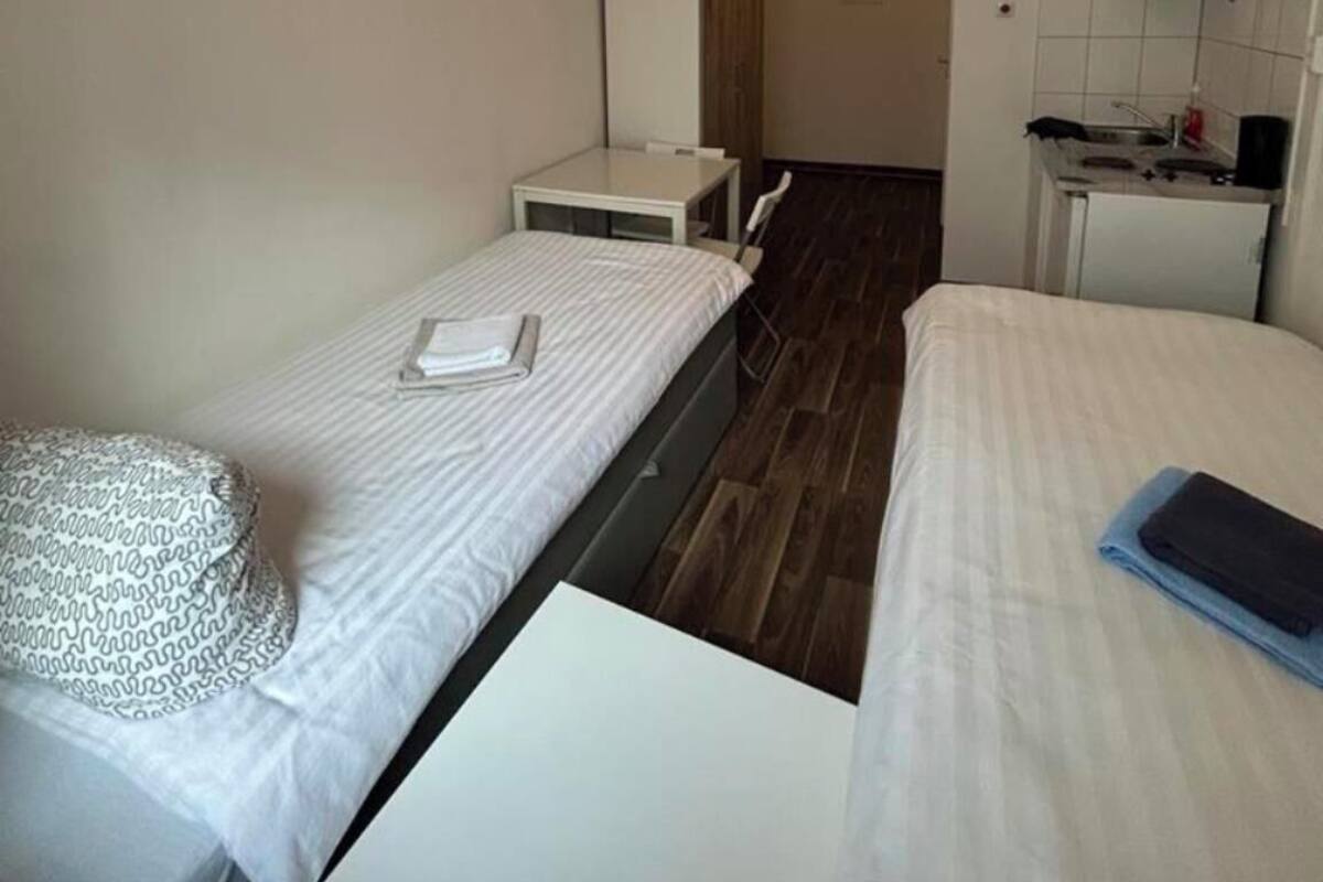 Une chambre d’hôtel compacte comprenant deux lits simples, une petite kitchenette et une salle de bain séparée.