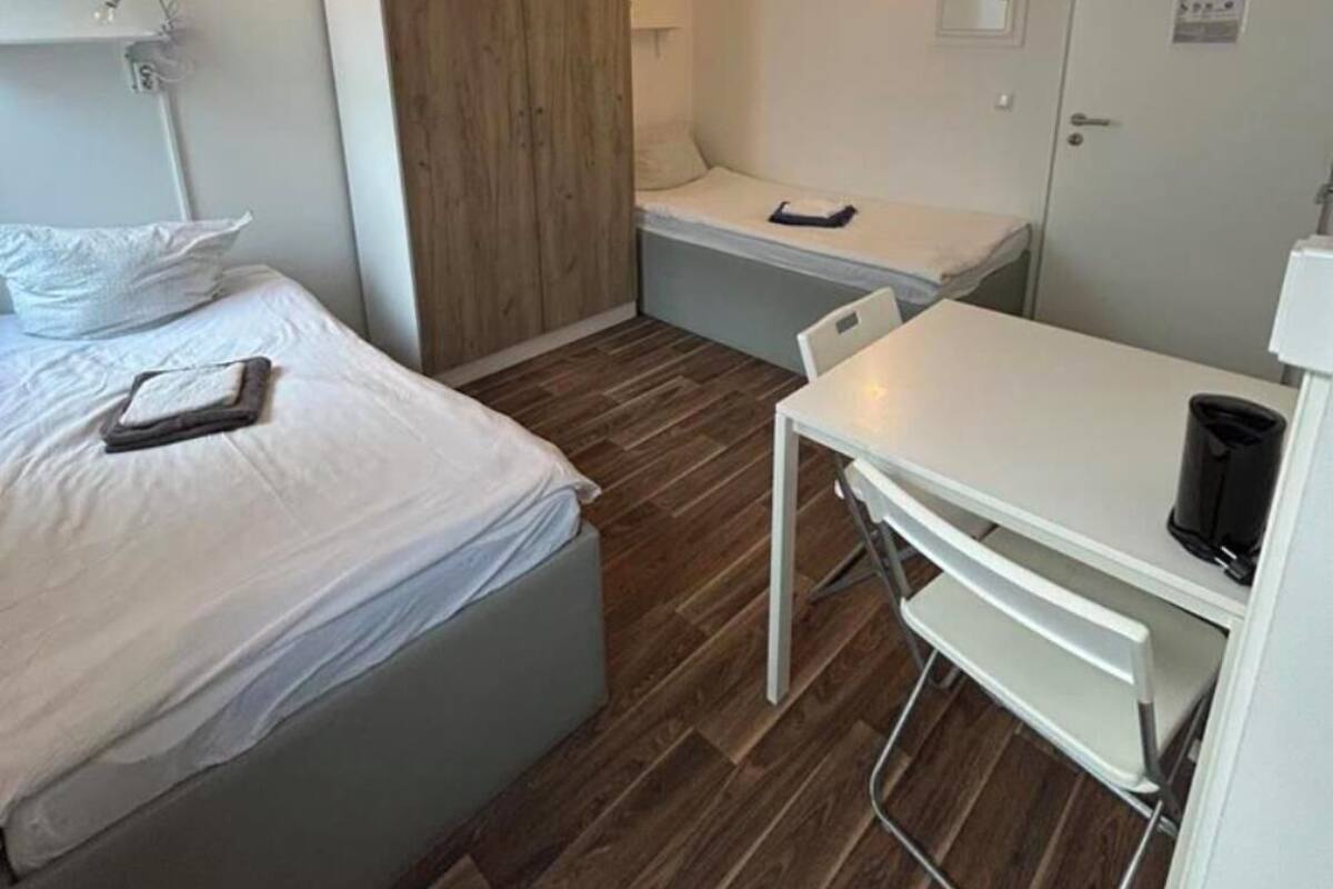Une chambre d’hôtel de taille réduite, comprenant un lit, un bureau et une armoire.
