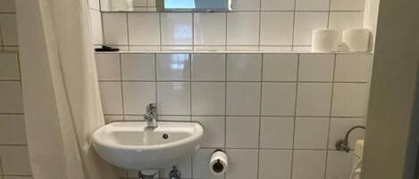 Un baño pequeño y funcional con un lavabo blanco, inodoro y un espejo sobre el lavabo.
