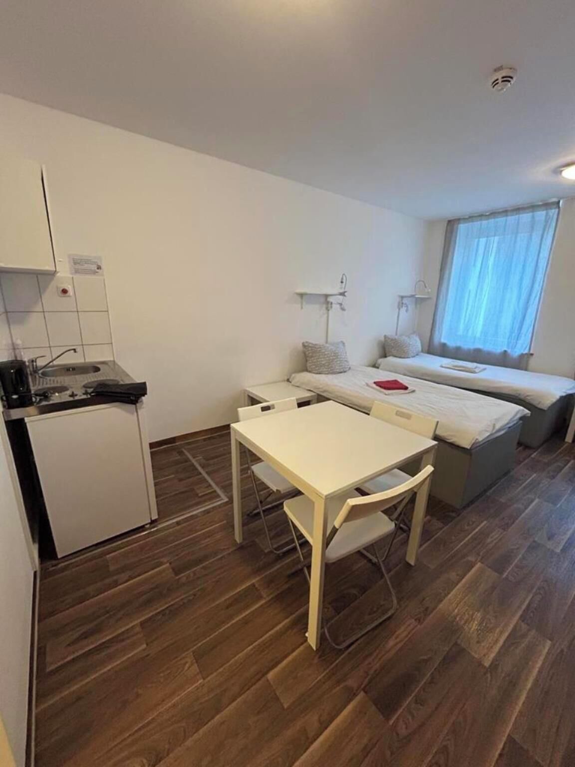Una habitación compacta con kitchenette, una pequeña mesa de comedor y una cama con ventana.