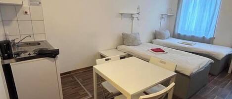 Una habitación compacta con kitchenette, una pequeña mesa de comedor y una cama con ventana.