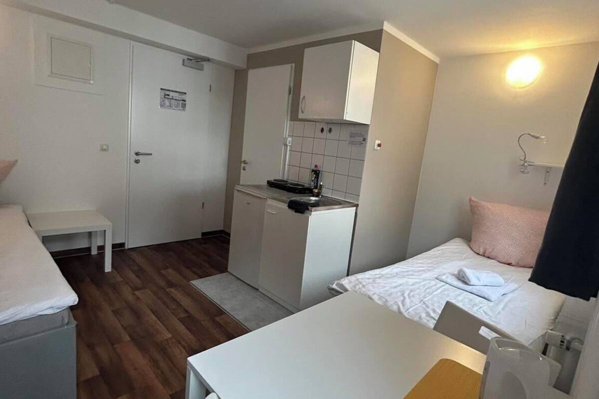 Une chambre d’hôtel compacte comprenant un coin cuisine, un lit, une petite table et une chaise.