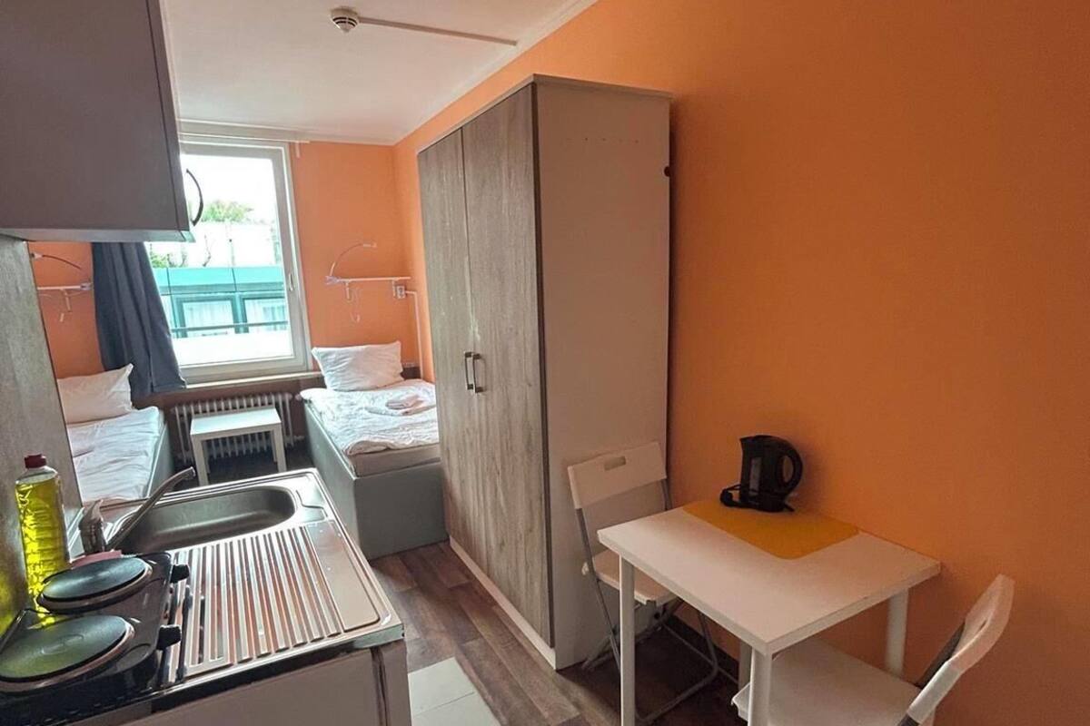 Une petite cuisine équipée comprenant un évier, une cuisinière et une petite table avec une chaise.