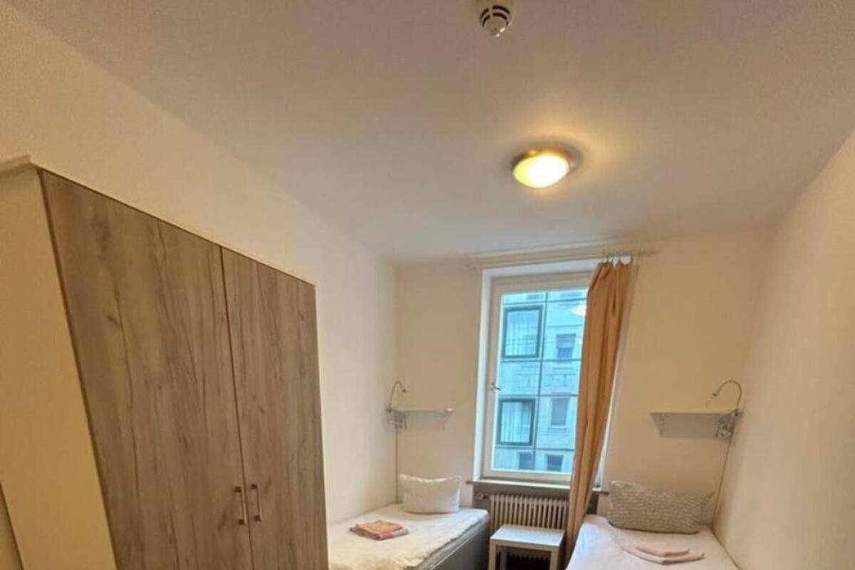 Une pièce de taille modeste, avec une armoire en bois, un petit lit, une table de chevet et un radiateur.