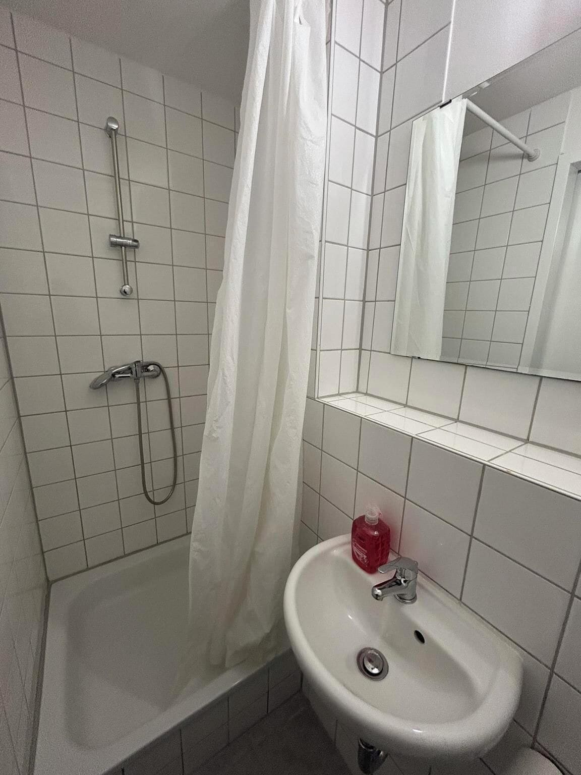 A bathroom with a shower, a sink, and a mirror.