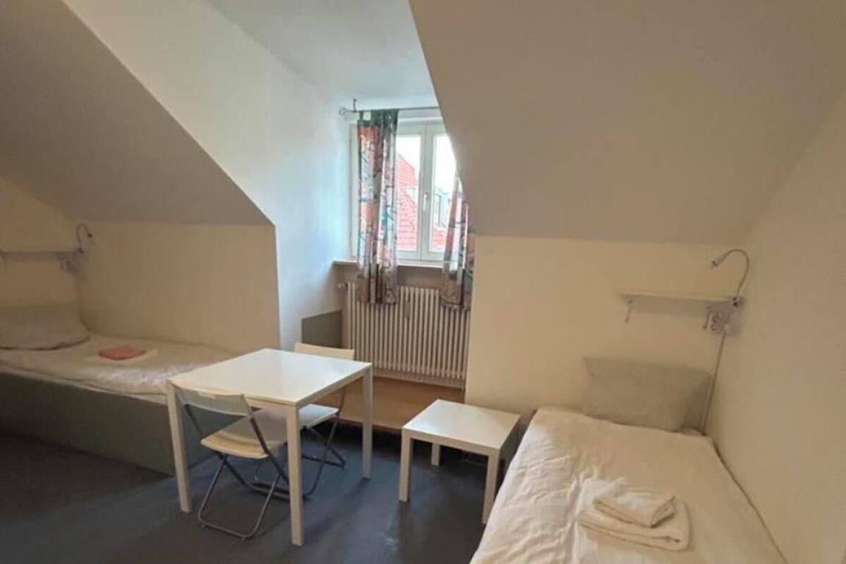 Une petite pièce mansardée triangulaire, avec un lit, une table et une chaise.