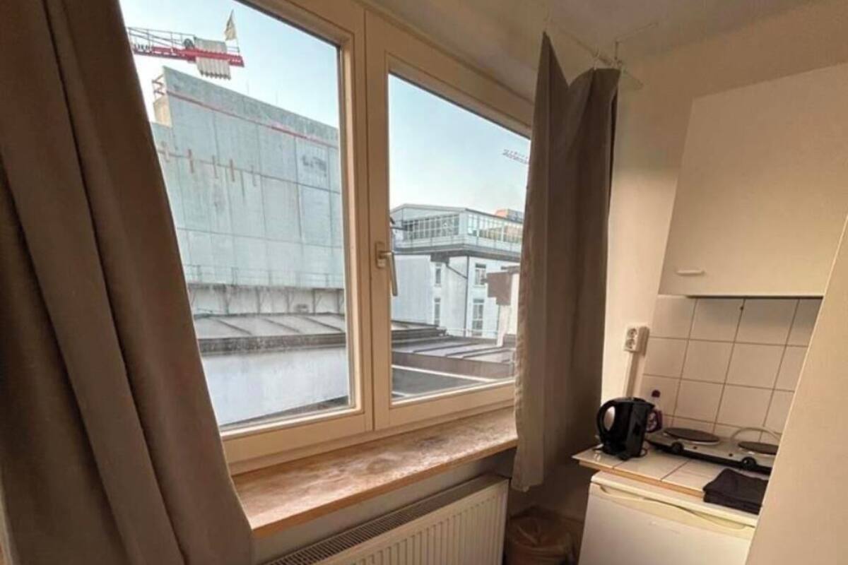 Une petite cuisine équipée avec une fenêtre donnant sur un chantier de construction.