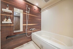 Une salle de bain moderne avec une grande baignoire blanche, un lambris en bois et des étagères intégrées où sont rangés les produits de toilette.