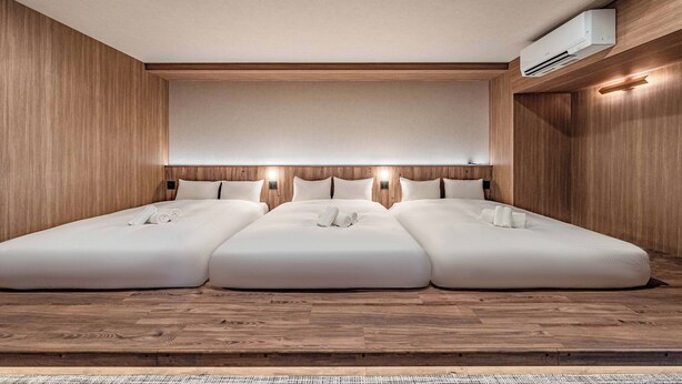 Una habitación de hotel con una cama grande, paneles de madera y un equipo de aire acondicionado.