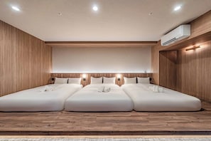 A hotel room with a large bed, wooden paneling, and an air conditioning unit.